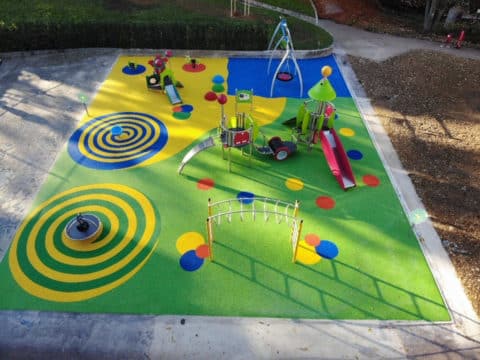 Vue aérienne d’une aire de jeux avec sols souples colorés, modules ludiques et structures à grimper