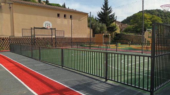Barrière de sécurité noire autour d'un terrain multisports avec une piste d'athlétisme autour