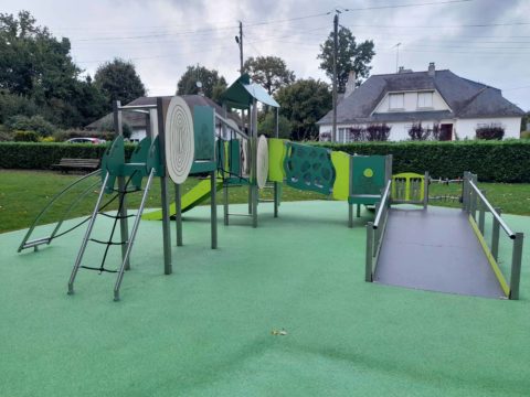 aire de jeux PMR Ludoparc avec rampe d’accès, toboggan et modules sensoriels sur sol souple vert dans un espace public.