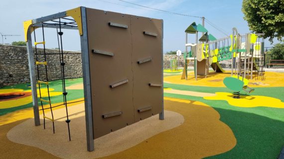 Module d'escalade avec mur d'escalade et filet sur aire de jeux modulaire colorée avec structures ludiques en arrière-plan