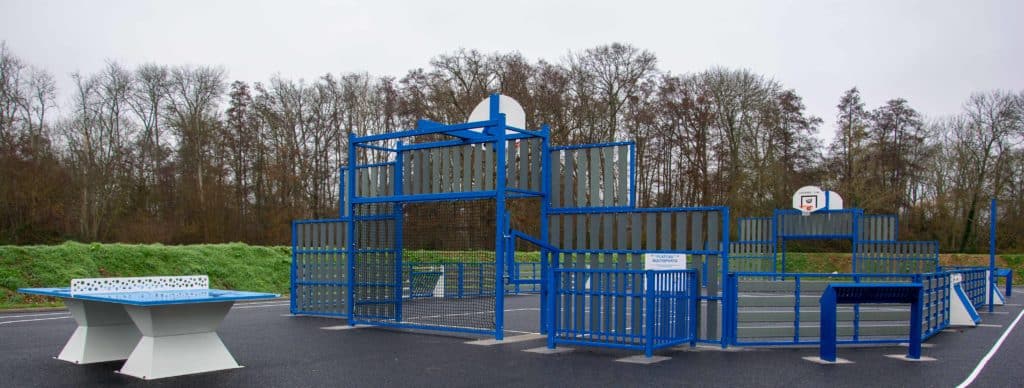 Terrain multisports avec équipements de basket et ping-pong installé dans un espace public.