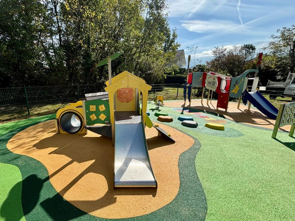 Aire de jeux pour enfants avec une structure ruche et son tunnel et toboggan.