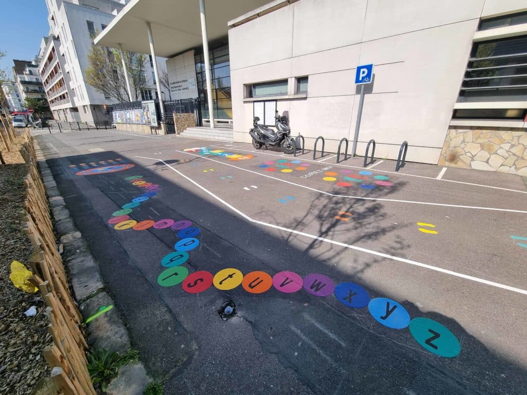 Marquage au sol ludique alphabet coloré et jeux sur le parvis scolaire.