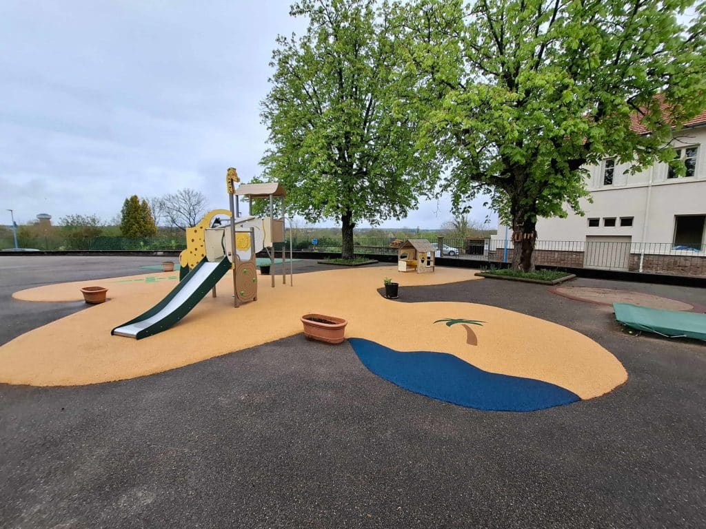 Aire de jeux thème safari et sol en résine sable et bleu dans une cour d'école